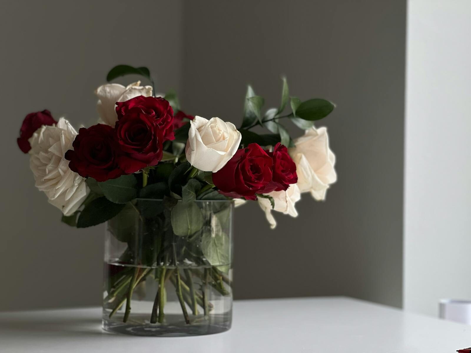 A beautiful arrangement of red and white roses in a clear glass vase on a table.