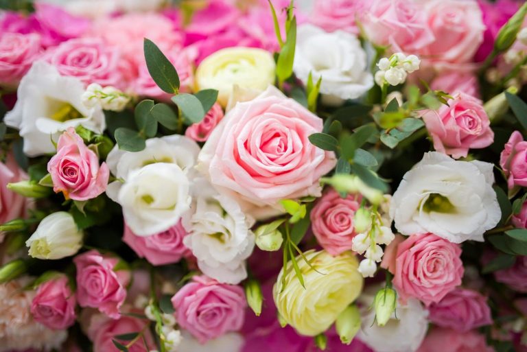 From above of bouquet of fresh delicate flowers with yellow and pink roses and green leaves