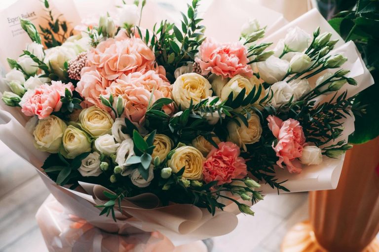 A vibrant bouquet featuring roses, carnations, and lush greenery in soft lighting.